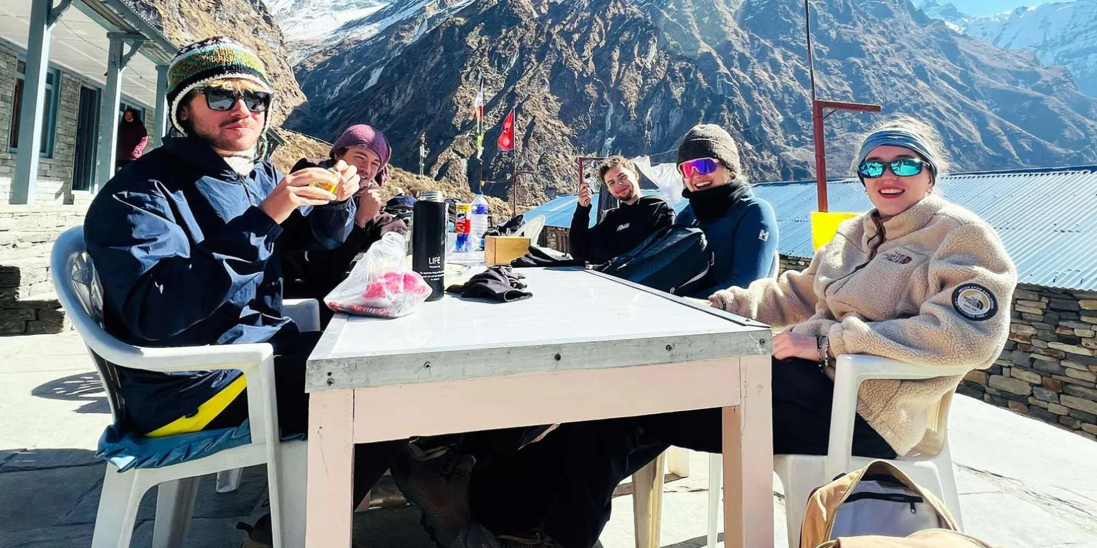 Trekkers resting with hot drinks on a guest-house terrace high in the Modi Khola valley