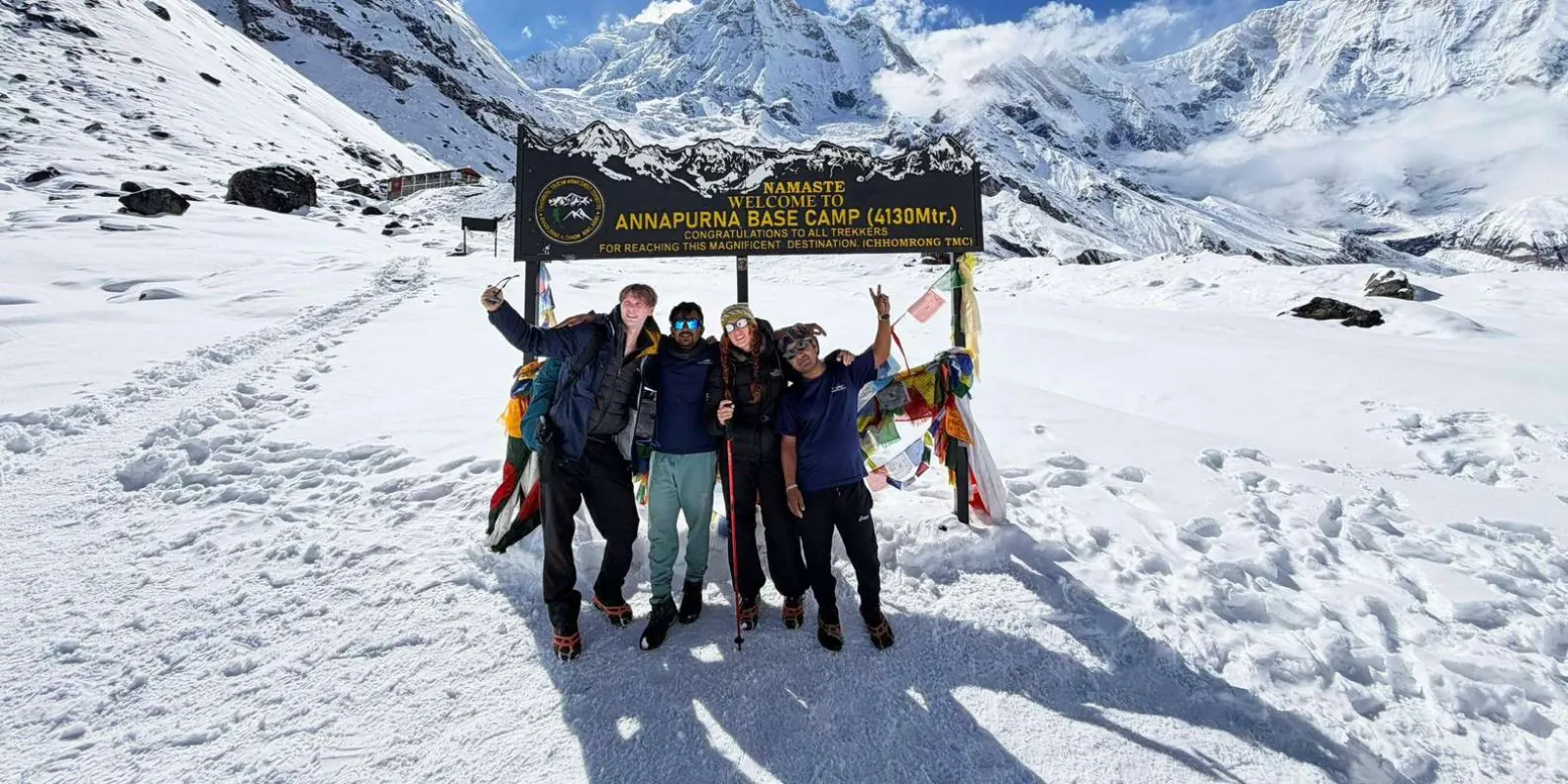 Trekking group and guide at the Annapurna Base Camp sign in deep winter snow