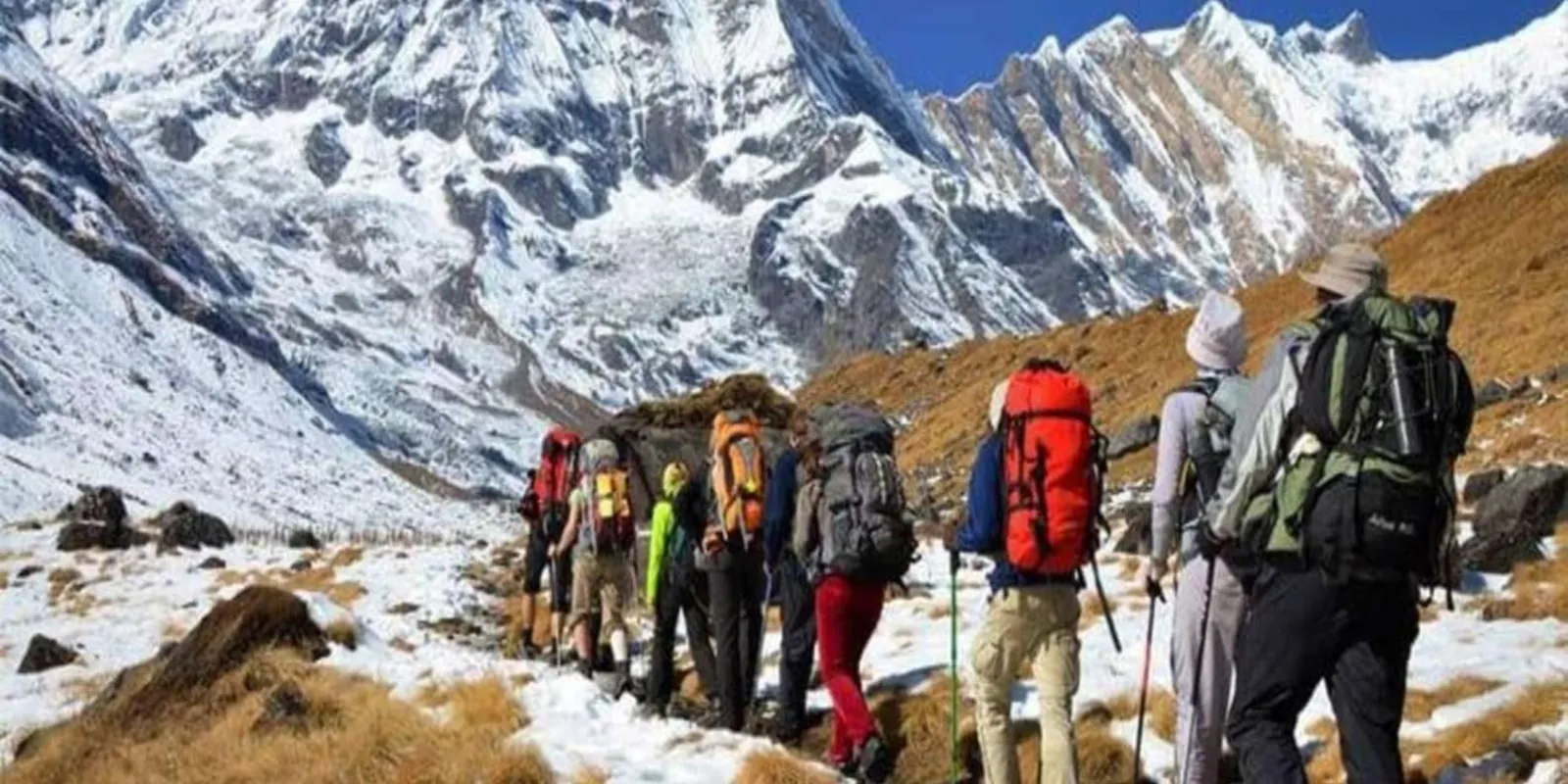 Line of trekkers with large packs climbing the snow-covered trail into the Annapurna Sanctuary